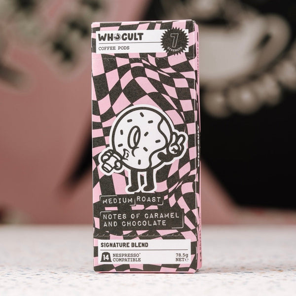 Whocult coffee pod packaging with a black and white checkered pattern on a blurred background